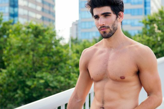 handsome shirtless sportsman in front of city buildings, concept of urban sport and healthy lifestyle, copy space for text