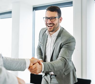 portrait of a young business man offering hand shaking hands introducing in the office