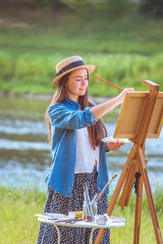 beautiful girl artist outdoor with wooden aesel and watercolor