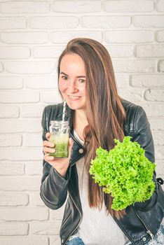 beautiful young smiling woman is drinking green detox shake . High quality photo