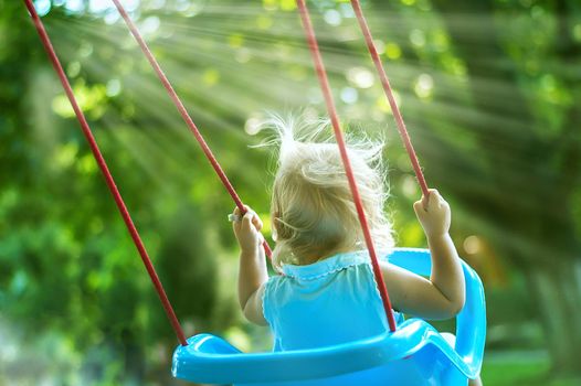 toddler girl on a swing in the park. High quality photo