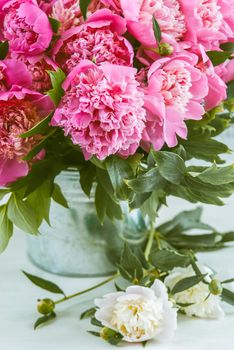 nice fresh pink peonies in tin bucket next to wooden background with space for text