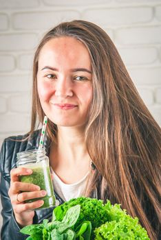 beautiful young smiling woman is drinking green detox shake . High quality photo