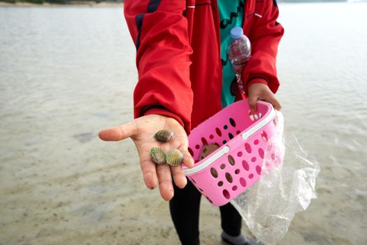 Ko Phangan, Thailand, March 15, 2022: woman showing the clams that collects on the sea