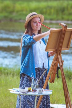 beautiful girl artist outdoor with wooden aesel and watercolor