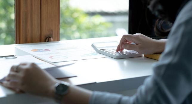 Business women work with calculator and laptop,pen and notebook on the wooden table.