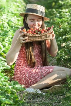 girl in strawberrry field with basket of fresh picked fruits