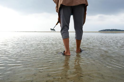 Ko Phangan, Thailand, March 15, 2022: legs of a woman searching for clams on the beach