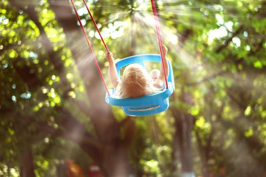 toddler girl on a swing in the park. High quality photo