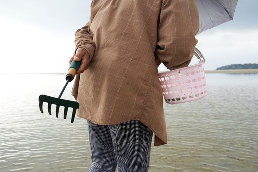 Ko Phangan, Thailand, March 15, 2022: person with a rake looking for clams on the sea