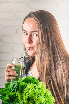 beautiful young smiling woman is drinking green detox shake . High quality photo