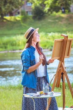 beautiful girl artist outdoor with wooden aesel and watercolor