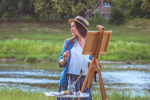 beautiful girl artist outdoor with wooden aesel and watercolor