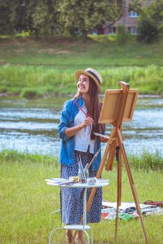 beautiful girl artist outdoor with wooden aesel and watercolor