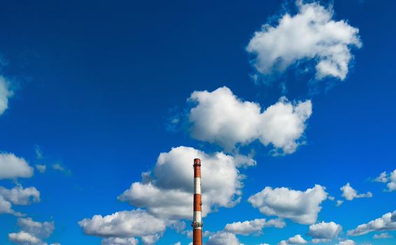 Boiler room chimney against a background of bright blue sky and white clouds