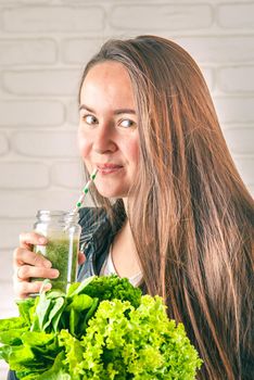 beautiful young smiling woman is drinking green detox shake . High quality photo