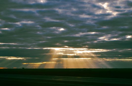 The rays of the sun make their way through the evening sky in the steppe