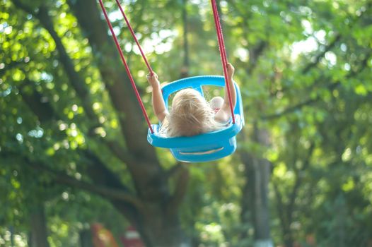 toddler girl on a swing in the park. High quality photo