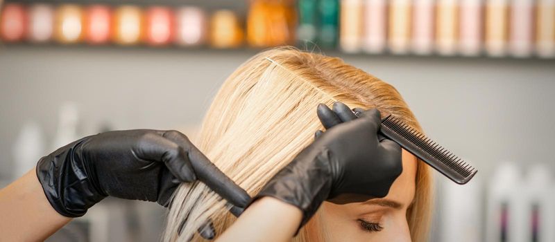 Hairdresser's hand combs female hair before dyeing in a beauty salon