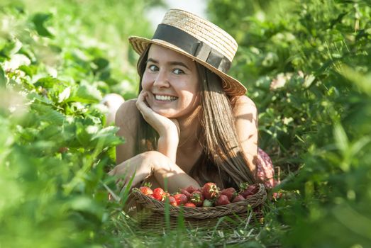 girl in strawberrry field with basket of fresh picked fruits