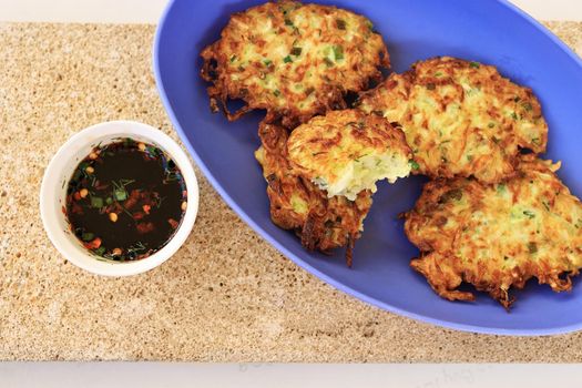 Zucchini fritters, vegetarian zucchini fritters on a blue oval platter served with soy sauce in a small white bowl. Vegetarian food