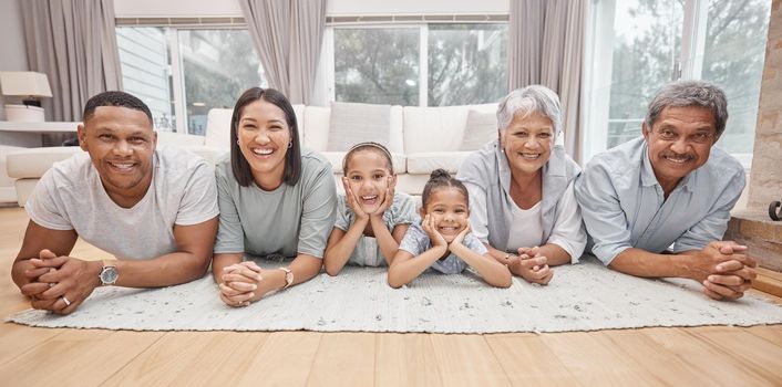 Happy and affectionate young mixed race family of six lying on the living room floor at home. Married couple with their mother, father and two cute daughters in the lounge. Granny and grandpa visit.