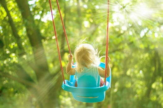 toddler girl on a swing in the park. High quality photo