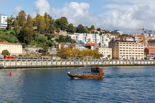 Porto, Portugal - October 23, 2020: Carlota do Douro tourist transport boat sailing on the Douro river showing the ancient city to visitors on an autumn day