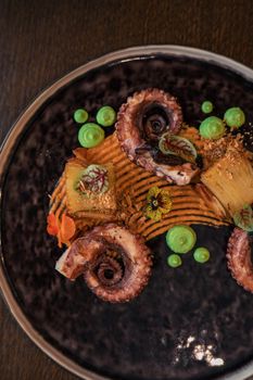 Octopus with potatoes on pea mash decorated with edible flowers