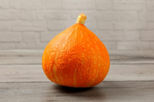 Red kuri squash (Hokaido pumpkin) on gray wood table.