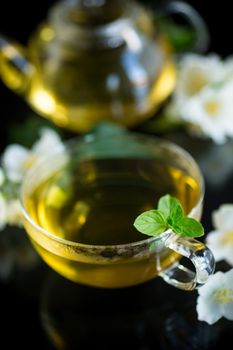 Composition with cup of jasmine tea and flowers isolated on black background