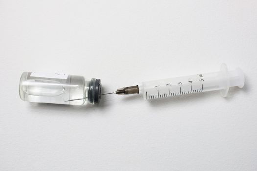 Ampoule with covid-19 vaccine and syringe on a white background..