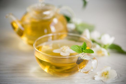 Composition with cup of jasmine tea and flowers on light background