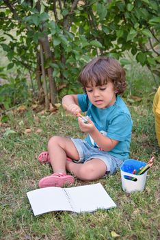 Elementary school age boys love to paint in parks. Boys are drawing pictures as an outdoor hobby. Concept of education outside of school