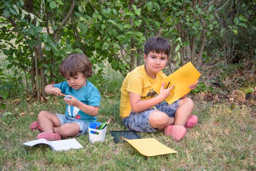 Back to school. Two happy and cheerful children, a schoolboy with notebooks and paints in their hands in the park