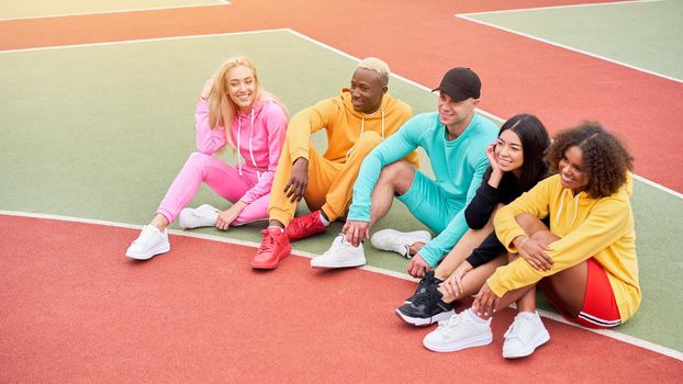 Multi-ethnic group teenage friends. African-american asian caucasian student spending time together Multiracial friendship Happy smiling People dressed colorful sportswear meeting outdoor sportground