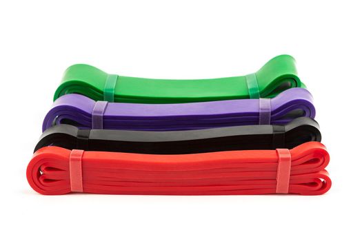 four multi-colored fitness elastic bands of different loads for training on muscle groups on a white background