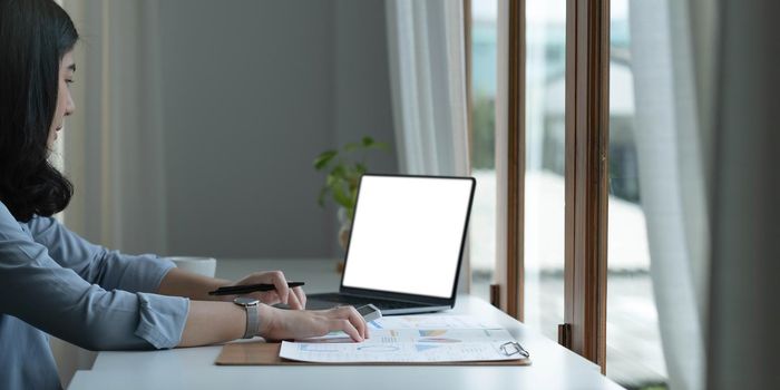 Woman working on laptop mock-up with blank copy space screen.