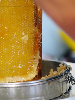 Natural raw honey being filtered ad dripped through a strainer to filter our bees wax.