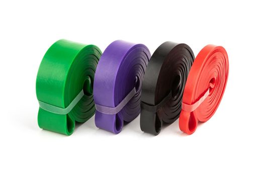 four multi-colored fitness elastic bands of different loads for training on muscle groups on a white background