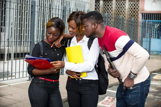 Students standing in the street after class looking at book smiling.