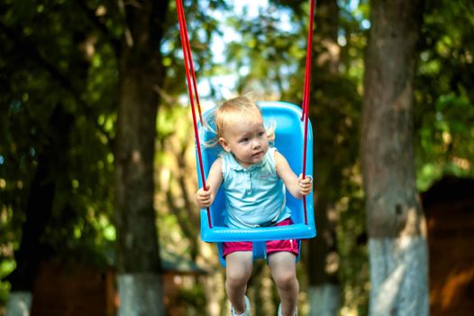 toddler girl on a swing in the park. High quality photo