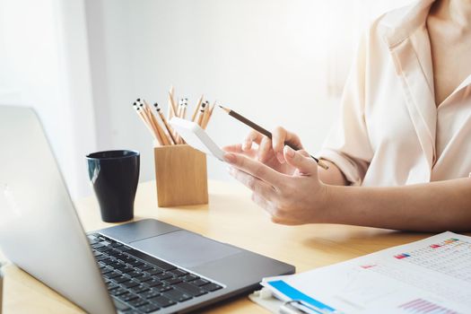 Business woman using calculator to review balance sheet annual with holding pen and using laptop computer to calculating budget. audit and Check integrity before investment concept