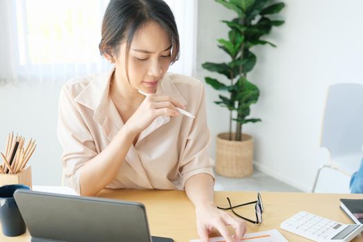 new normal, a businesswoman using tablet to work for a company Via the internet on your desk at home