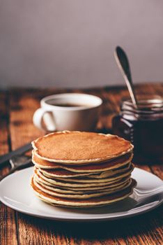 Stack of pancakes on white plate over wooden surface