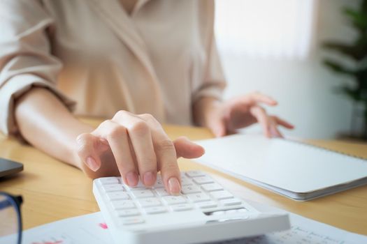 Business woman using calculator to review balance sheet annual using document and laptop computer to calculating budget. audit and Check integrity before investment concept