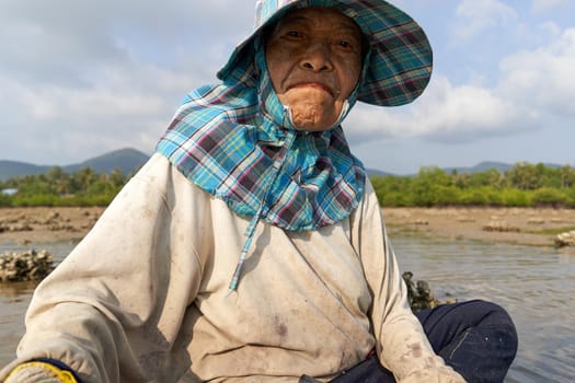 Ko Phangan, Thailand, March 15, 2022: portrait of a smiley old woman working collecting clams