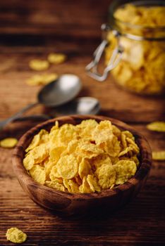 Corn flakes in a wooden bowl on rustic surface