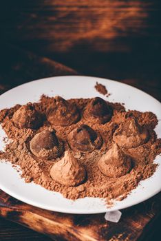 Homemade chocolate truffles coated in cocoa powder on white plate