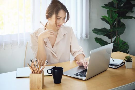 new normal, a businesswoman uses a computer to work for a company Via the internet on your desk at home.